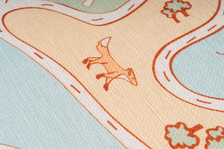 Detailaufnahme eines Kinderteppichs mit gewebter Oberfläche und Motiven wie Straßen, einem Fuchs und Bäumen.