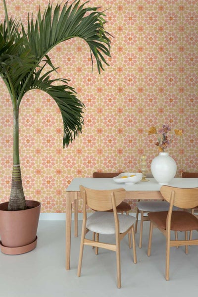 Heller Essbereich mit geometrisch gemusterter Tapete, Holztisch, Stühlen und einer großen Zimmerpalme.
