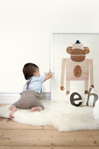 Szene mit einem Baby auf einem Schaffellteppich, das nach einem gerahmten Bild von einem Affen greift