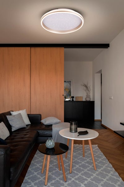 Wohnzimmer mit Led Deckenleuchte, Sofa und Couchtischen.