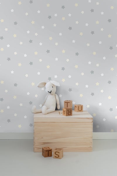 Kinderzimmer mit Babybett, Kissen und Sternentapete