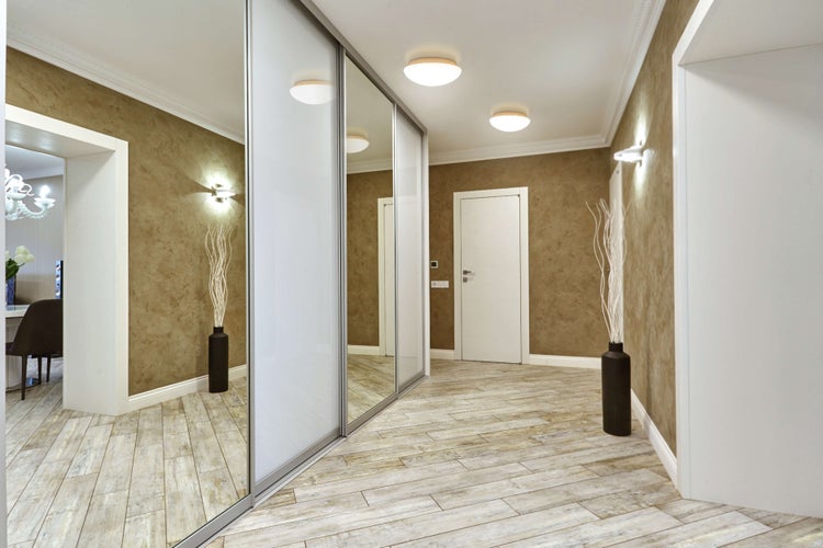 Flur mit Schiebetürenschrank, Holzboden und Wandleuchten