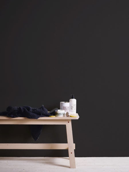 Dekoratives Stillleben mit Spiegel, Vase und Blatt auf einem Tisch vor einer dunklen Wand