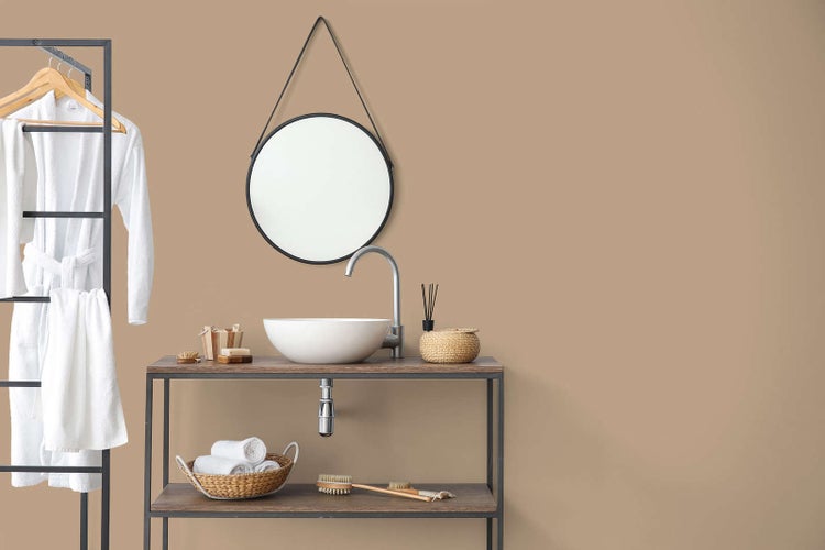 Modernes Badezimmer mit beiger Wand, einem hölzernen Waschtisch mit weißem Aufsatzbecken, einer Chromarmatur und einem runden Hängespiegel.