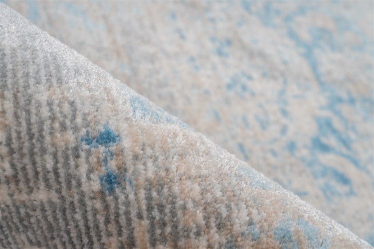 Nahaufnahme eines weichen Teppichs mit abstraktem Muster in Blau und Beige, gewebte Struktur.