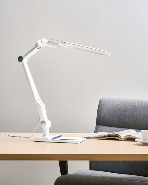 Weiße LED-Schreibtischleuchte auf Schreibtisch mit Notizblock, Stift und Magazin