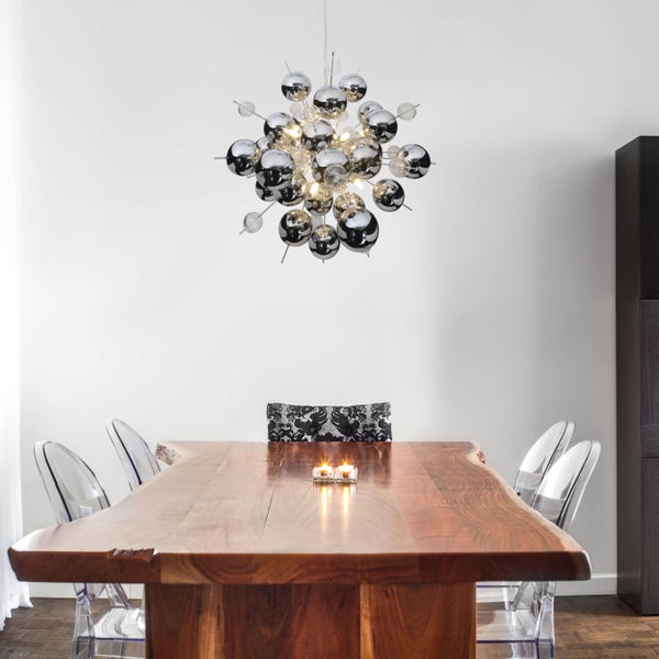 Esszimmer mit Esstisch aus Holz, transparenten Stühlen und einer Kugelleuchte