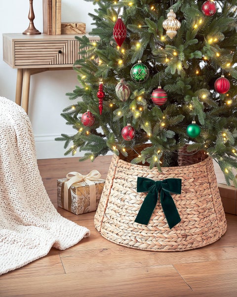 Weihnachtsbaumständer in Korboptik mit Schleife für den Weihnachtsbaum im Wohnzimmer.
