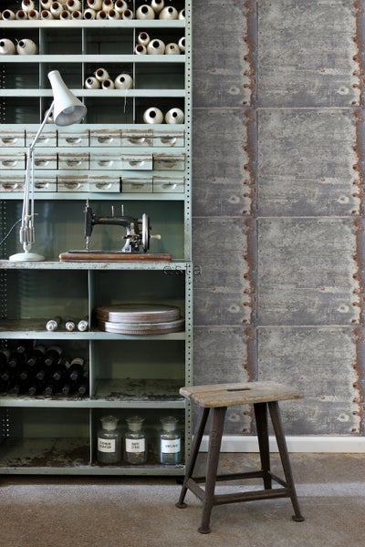 Regal mit Nähzubehör, Lampe und Dekoration neben einer Fototapete mit industriellem Design und einem Hocker.