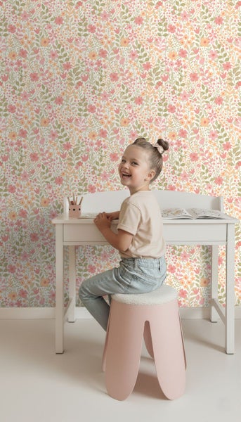 Mädchen am Schreibtisch vor einer Wand mit Blumentapete