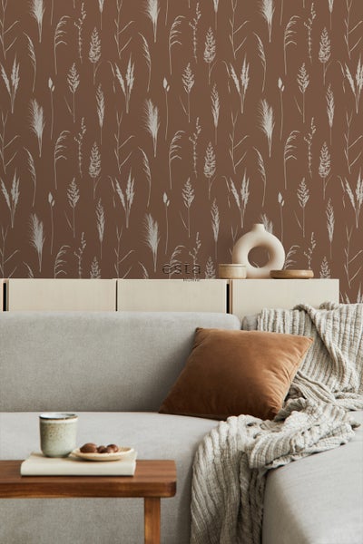 Wohnzimmer mit brauner Tapete mit Gräser-Muster, Sofa, Kissen, Decke und Beistelltisch.