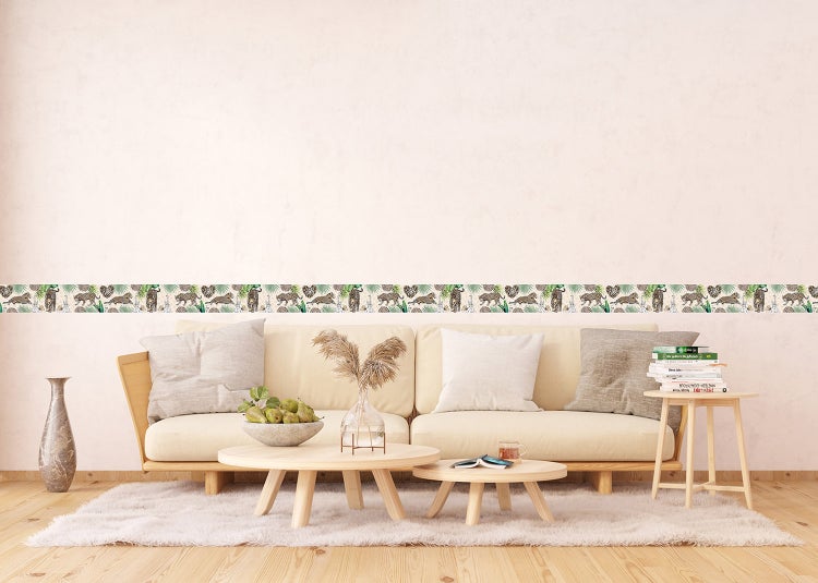 Tapetenbordüre mit Leoparden- und Dschungelmotiv in einem hellen, modern eingerichteten Wohnzimmer mit Holzmöbeln.
