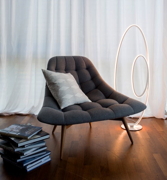 Grauer Sessel mit Kissen und einer LED-Stehlampe im Raum