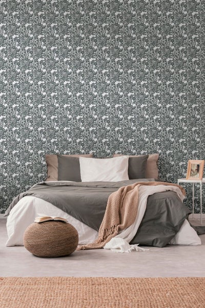 Schlafzimmer mit Bett vor einer gemusterten Tapete mit floralem Design