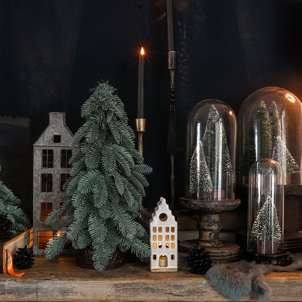 Dekoratives Arrangement mit Weihnachtsbäumen, Hauslaternen und Kerzenständern für eine festliche Atmosphäre.