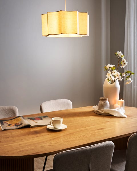 Esstisch mit Pendelleuchte, Stühlen, Blumenvase, Kerzen, Tasse und Zeitschrift für eine gemütliche Atmosphäre