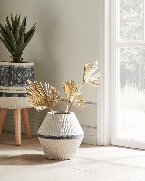 Dekorative Szene mit Pflanzgefäßen und getrockneten Palmen in einem hellen Raum.
