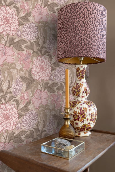 Dekoratives Zimmer mit Blumentapete, Tischleuchte, Kerzenständer und Holzbeistelltisch.