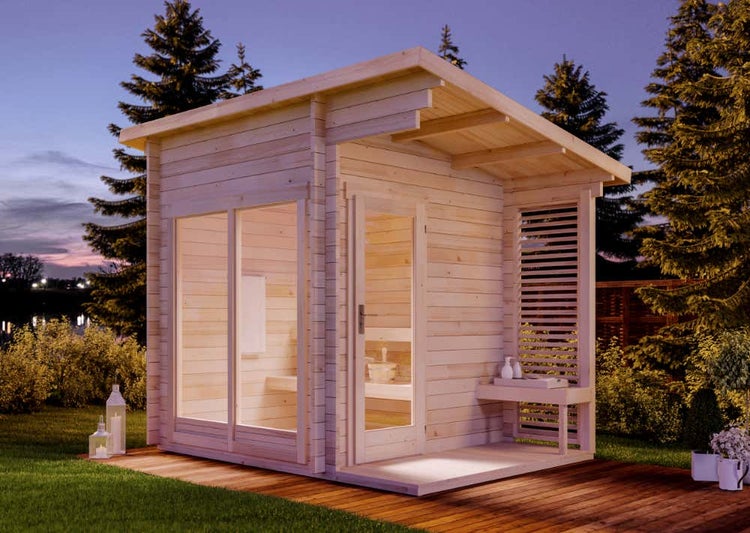Moderne Gartensauna aus Holz mit Pultdach, großer Glasfront und überdachtem Vorbereich mit Sichtschutzwand in einer Gartenlandschaft.