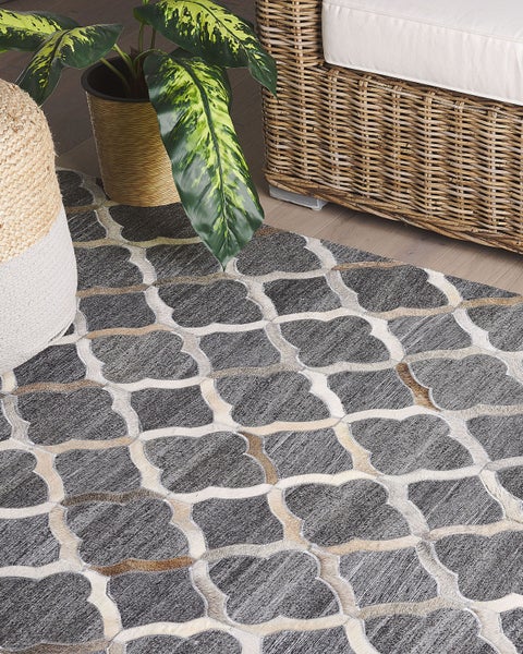 Dekorativer Teppich mit Muster neben Korbmöbeln und Topfpflanze