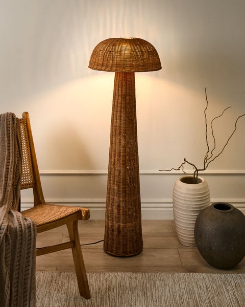 Szene mit Rattanständerleuchte, Stuhl, Decke und Vasen.