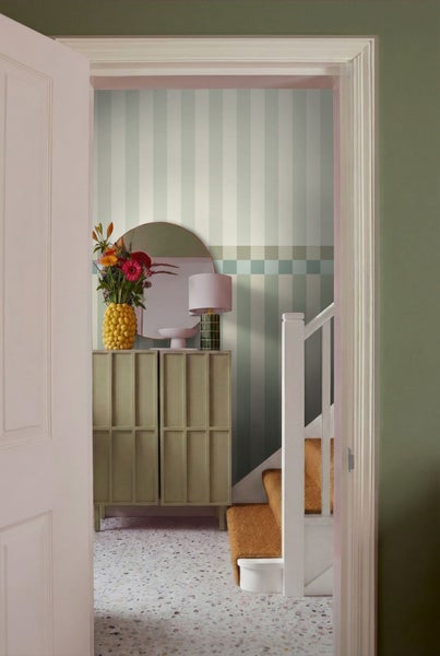 Flur mit Kommode, Spiegel, Lampe, Blumenvase, Treppe und gestreifter Tapete