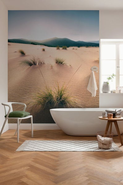 Modernes Badezimmer mit Badewanne, Stuhl und Fototapete mit Dünenmotiv