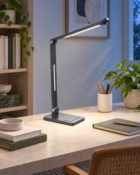 Moderne LED Schreibtischleuchte mit verstellbarem Gelenkarm und integrierter Ladefunktion auf einem Schreibtisch in einer Wohnumgebung.