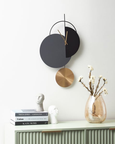 Dekoratives Zimmer mit einer modernen Wanduhr, einer Blumenvase und dekorativen Büchern