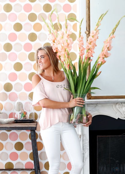 Frau mit Gladiolenstrauß vor gepunkteter Tapete