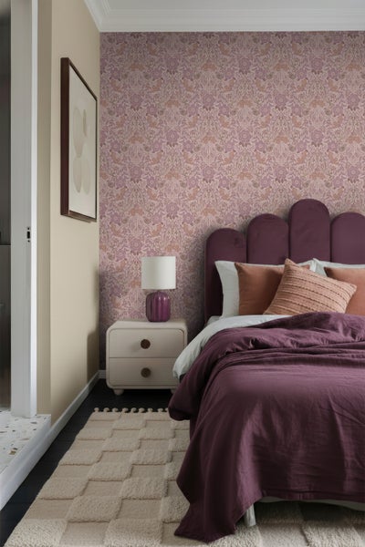 Schlafzimmer mit Blumenmustertapete, Bett, Nachttischlampe und Teppich