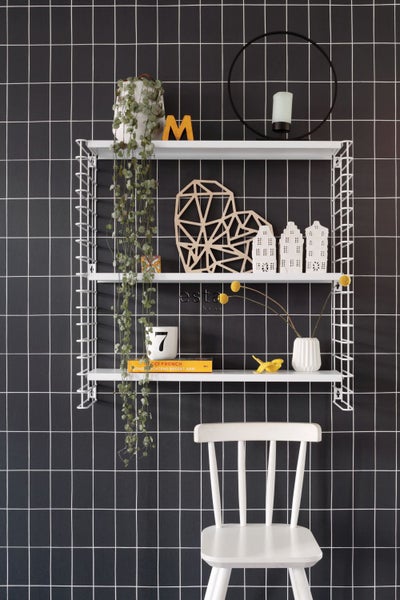 Dekoratives Wandregal mit verschiedenen Dekorationsgegenständen und einem Stuhl