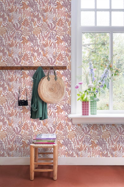 Raum mit floraler Tapete, Fenster, Hocker und Accessoires wie Tasche und Jacke.