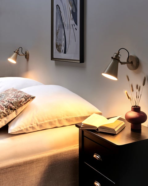 Schlafzimmer-Szene mit Bett, Nachttisch, Wandleuchten und Dekorationen für eine gemütliche Atmosphäre