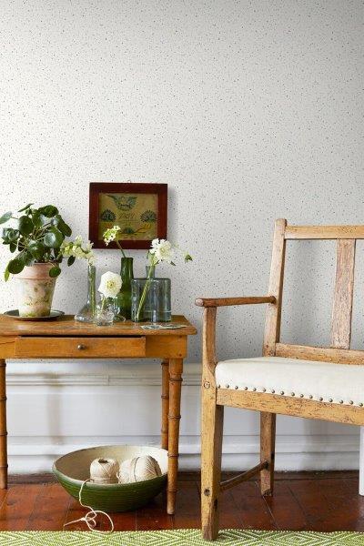 Wohnzimmer mit gemusterter Tapete, Couch, Teppich und Zimmerpflanze.