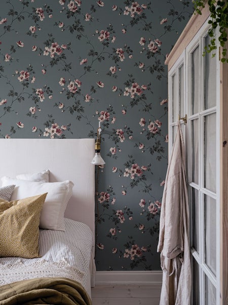 Schlafzimmer mit blumiger Tapete, Bett und Kleiderschrank