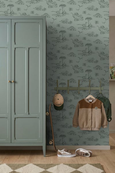 Tapete mit Dinosaurier-Motiv in einem Kinderzimmer mit grünem Kleiderschrank und Wandgarderobe.