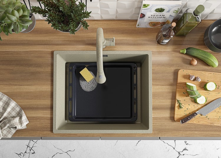 Küchenspüle mit Armatur, Backblech und Spülschwamm auf einer Küchentheke.