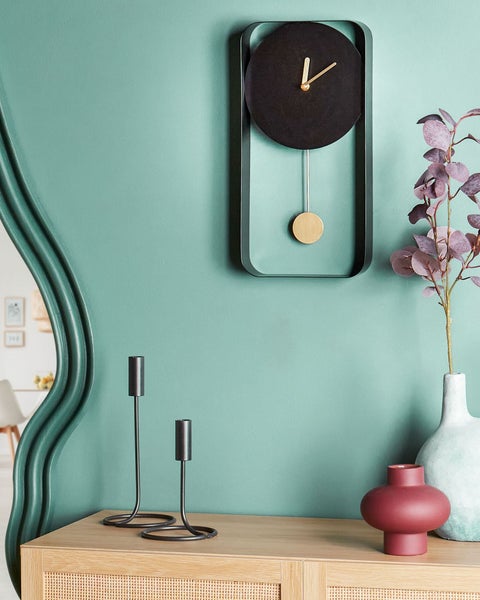 Dekorative Szene mit Pendeluhr, Kerzenhaltern und Vasen auf einem Holzschrank