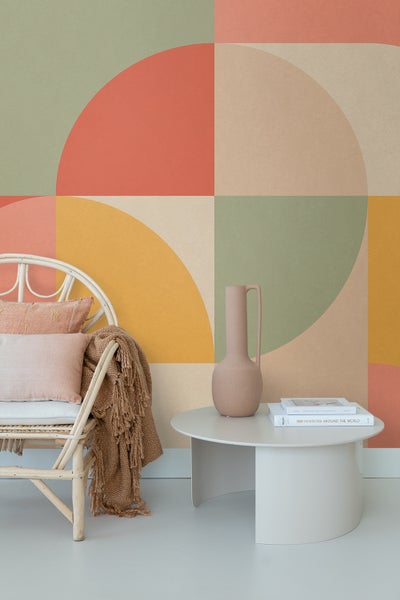 Wohnraum mit Rattan-Stuhl, Tisch und geometrischer Mustertapete