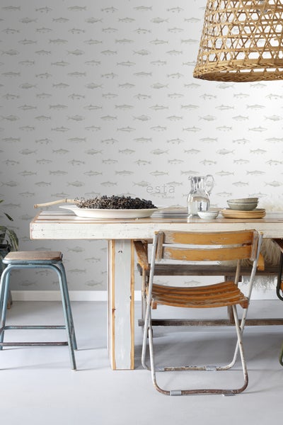 Dekoratives Interieur mit Mustertapete, Holztisch, Stühlen und geflochtener Lampe