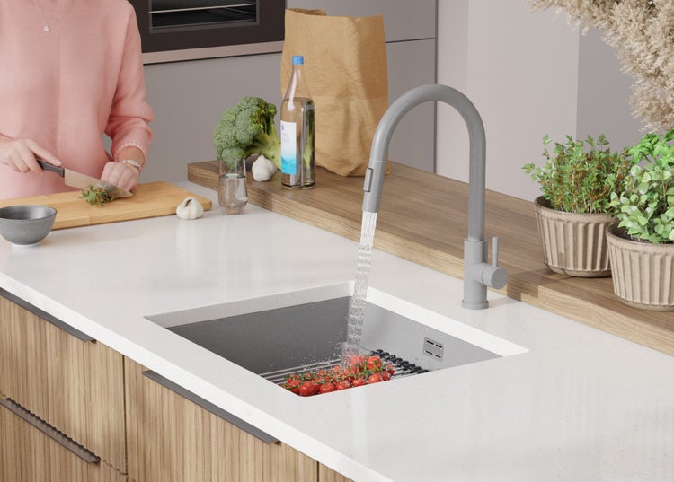 Moderne Küche mit Spüle, Armatur und Person, die Gemüse schneidet