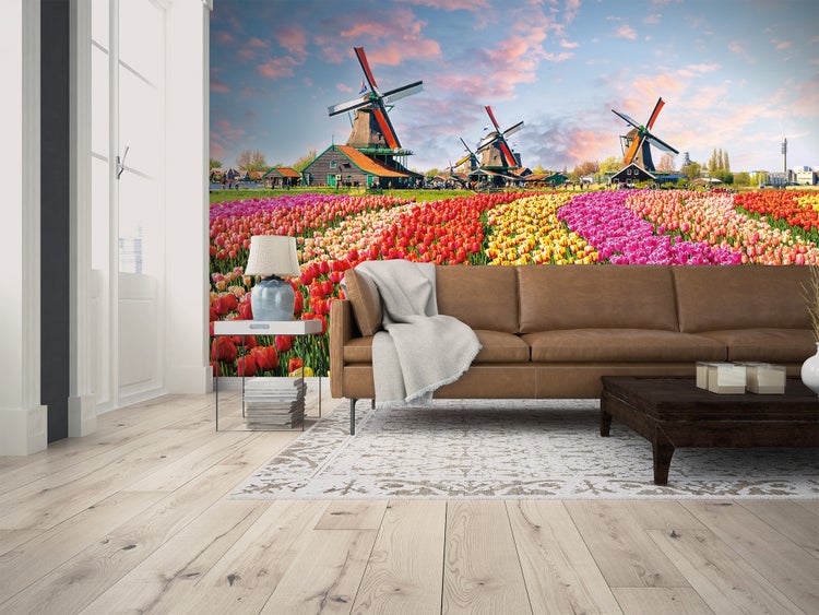 Fototapete mit niederländischer Landschaft, Windmühlen und Tulpenfeld in einem hellen Wohnzimmer mit Ledersofa und Holzfußboden.