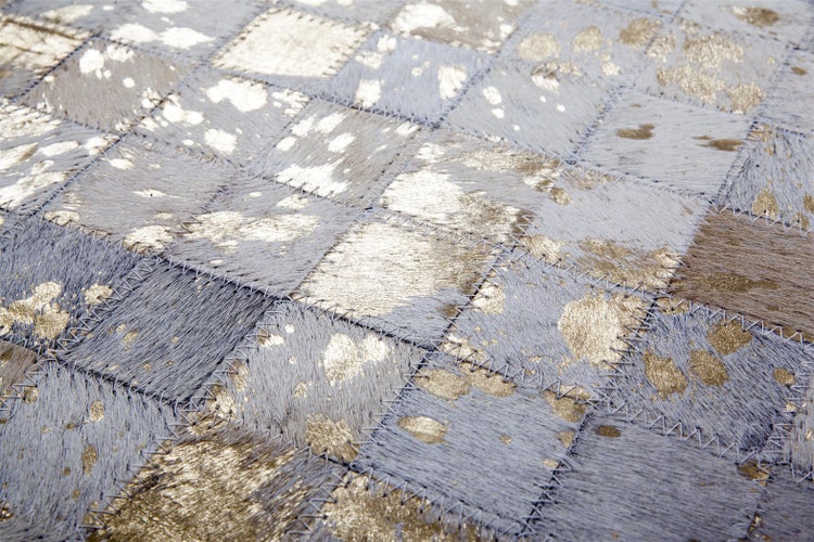 Rechteckiger Teppich mit Patchwork-Muster und schimmernden Goldakzenten.