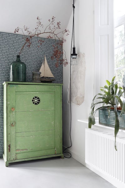 Dekoratives Interieur mit einem grünen Schrank, einer Flasche und einem kleinen Segelboot