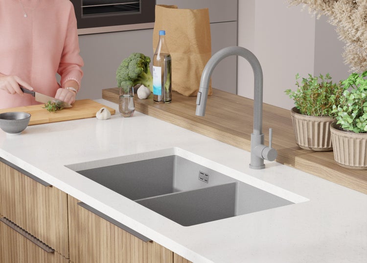 Küchenszene mit Spüle, Armatur und Person beim Kochen