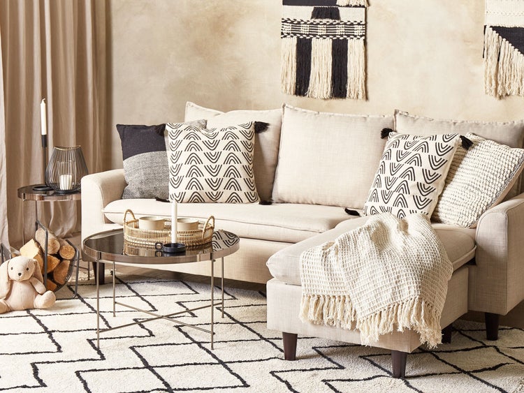 Wohnzimmer mit Sofa, Kissen, Teppich und dekorativen Elementen für eine gemütliche Atmosphäre.