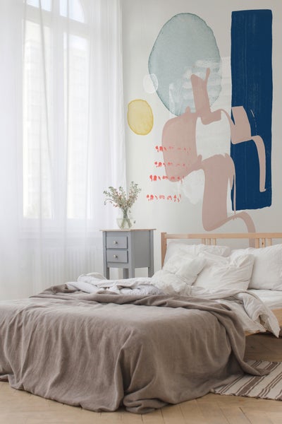 Helles Schlafzimmer mit einer großflächigen, abstrakten Wandtapete mit organischen Formen hinter einem Holzbett und einem grauen Nachttisch.