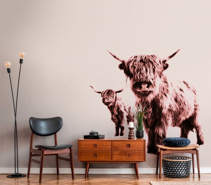 Fototapete mit schottischen Hochlandrindern in einem modern eingerichteten Wohnraum mit Sideboard, schwarzem Stuhl und einer Stehlampe.