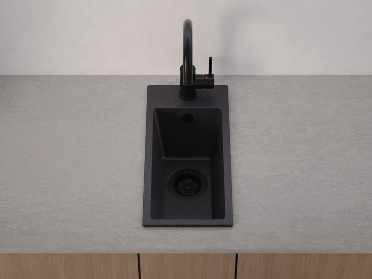 Einbauspüle aus Quarzkomposit in Schwarz mit schwarzer Küchenarmatur, eingebaut in eine Arbeitsplatte.